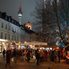 Feuerzangenbowle im Nikolaiviertel Berlin Leute trinken abends auf dem Kirchplatz Fernsehturm im Hintergrund